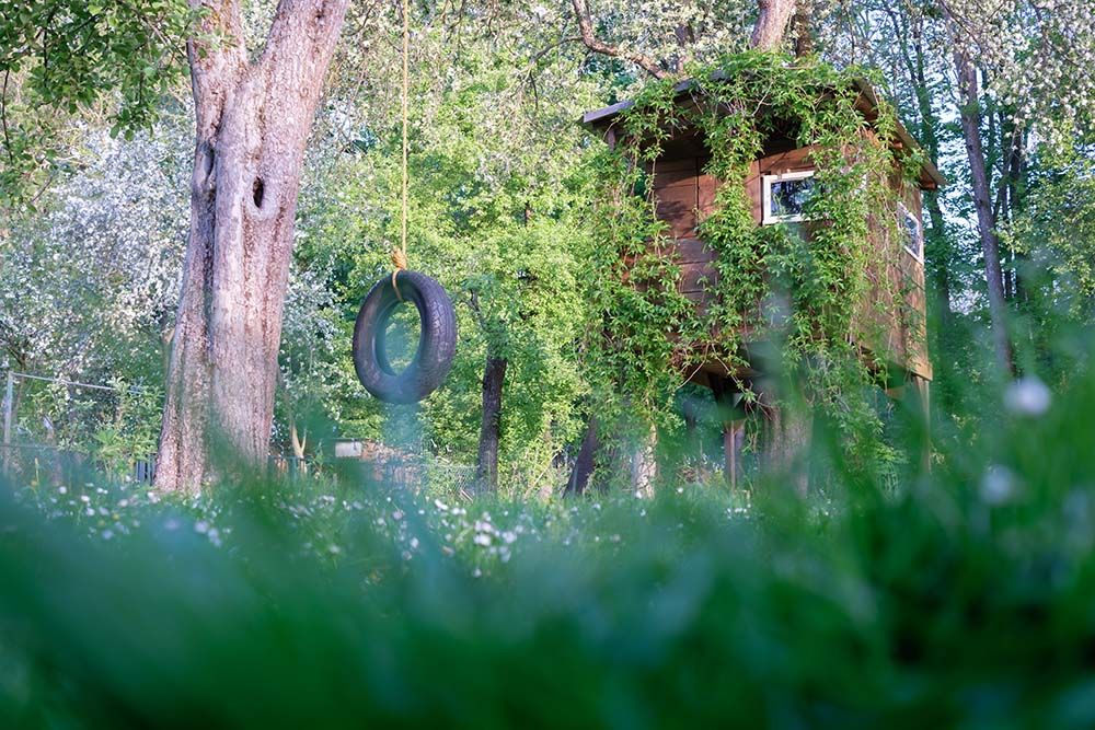 Ein verwegenes Baumhaus in einem blühendem Garten.